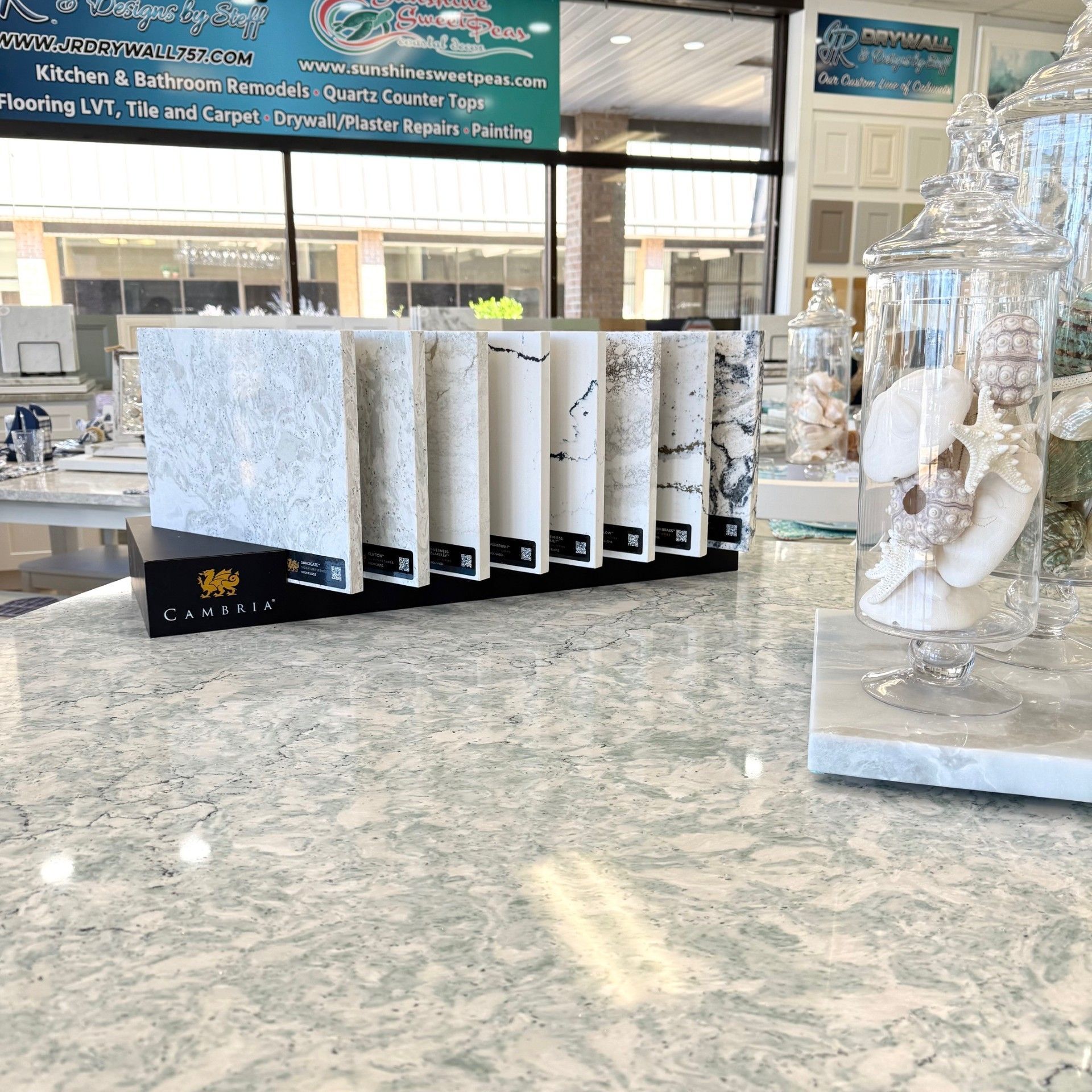 Display of stone samples with a glass jar containing seashells on a countertop.