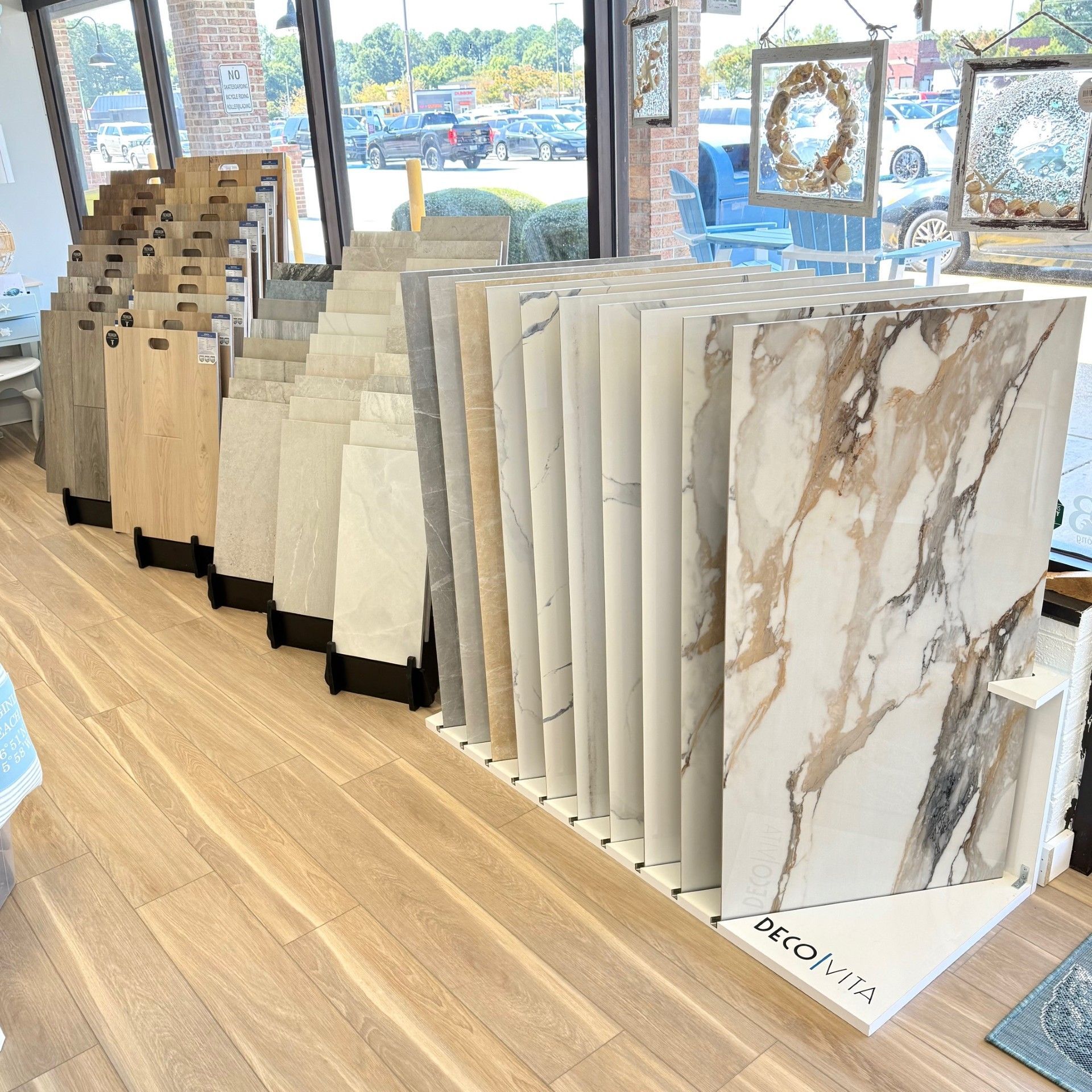 Tile samples displayed in a store, showcasing various colors and patterns, lit by natural light.