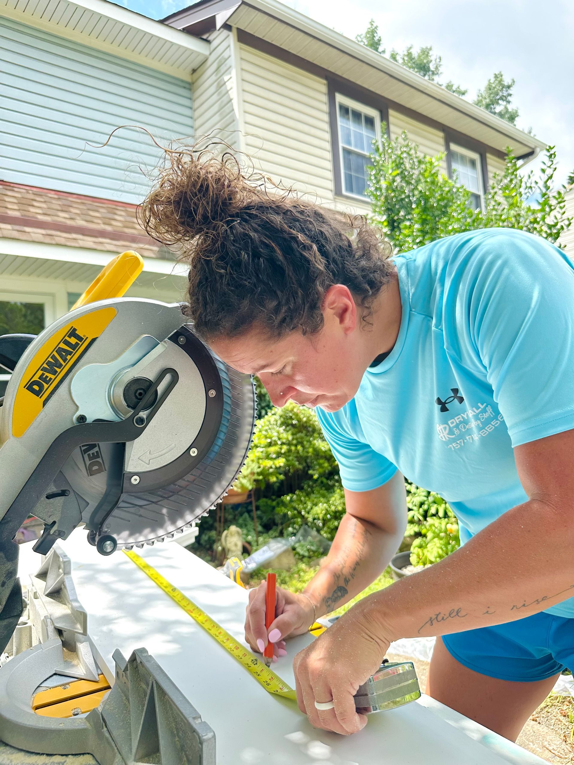 Woman using a miter saw outdoors, measuring and marking a board.
