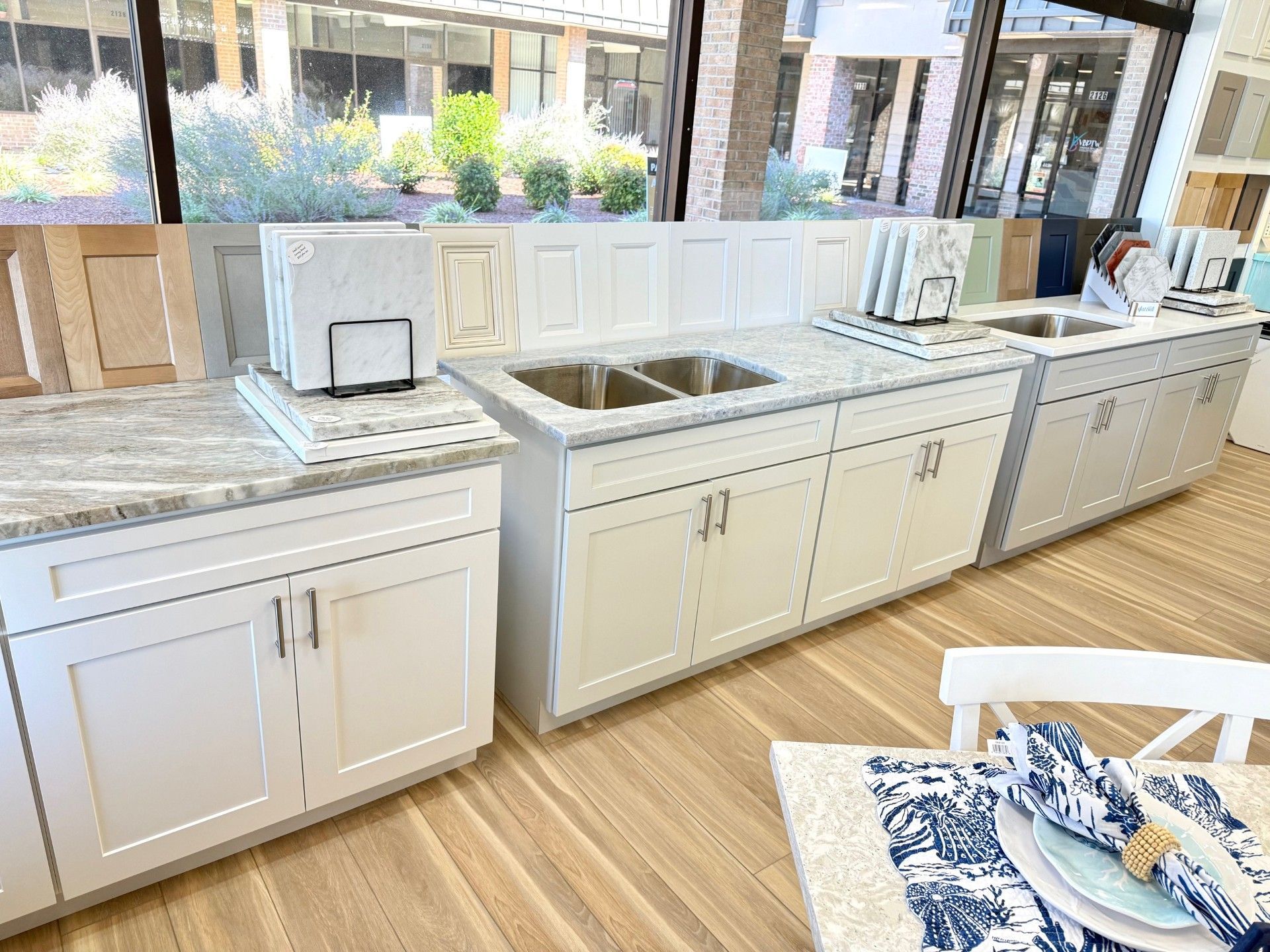 Kitchen cabinets in a showroom, with countertops and samples in a well-lit space.
