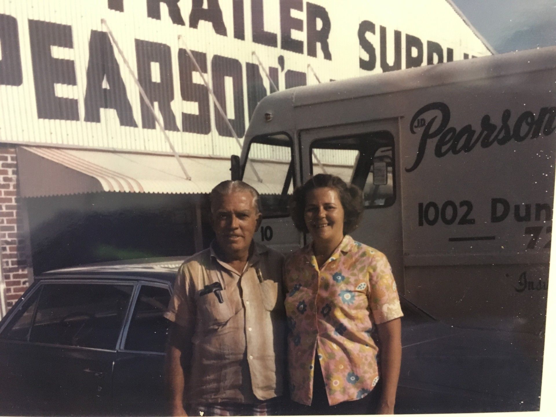 An older couple stands in front of a delivery truck