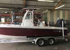 A maroon and white center console boat on a metal trailer inside a storage warehouse.