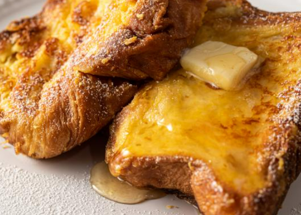 Two pieces of golden-brown French toast on a plate, topped with a melting pat of butter and syrup.