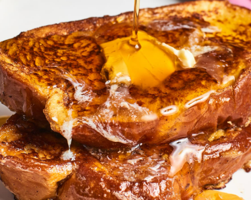 Golden-brown French toast topped with melting butter and drizzled with syrup.