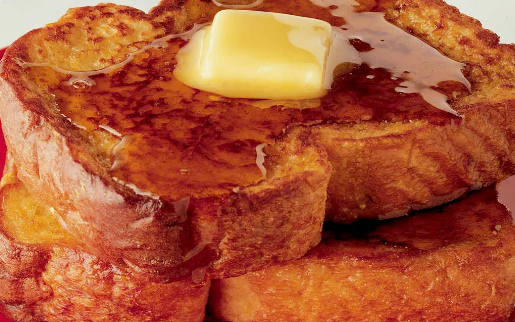 A stack of golden-brown French toast slices topped with a melting pat of butter and drizzled with maple syrup.
