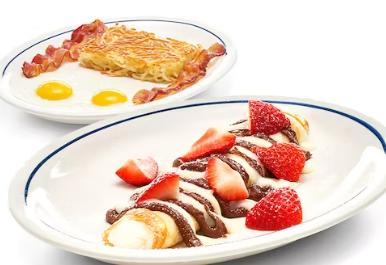 Two plates of food: one with eggs, bacon, and hash browns, the other with strawberry and chocolate crepes.
