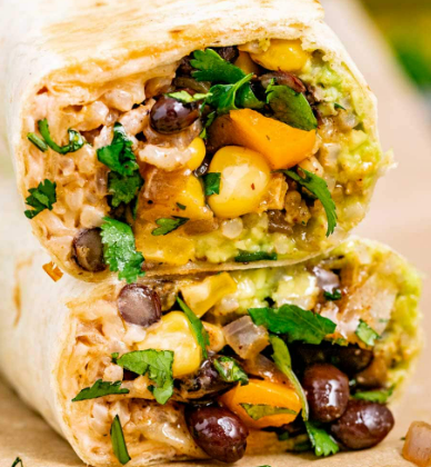 Two halves of a vegetarian burrito showing black beans, corn, chopped onions, and cilantro inside a flour tortilla.