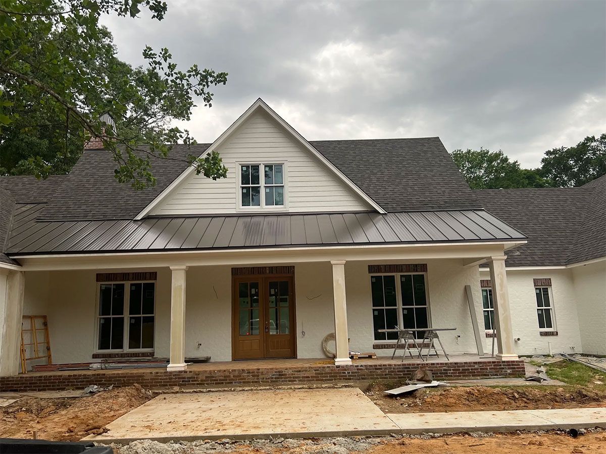 Front porch of a house under construction with unfinished siding and exposed foundation.