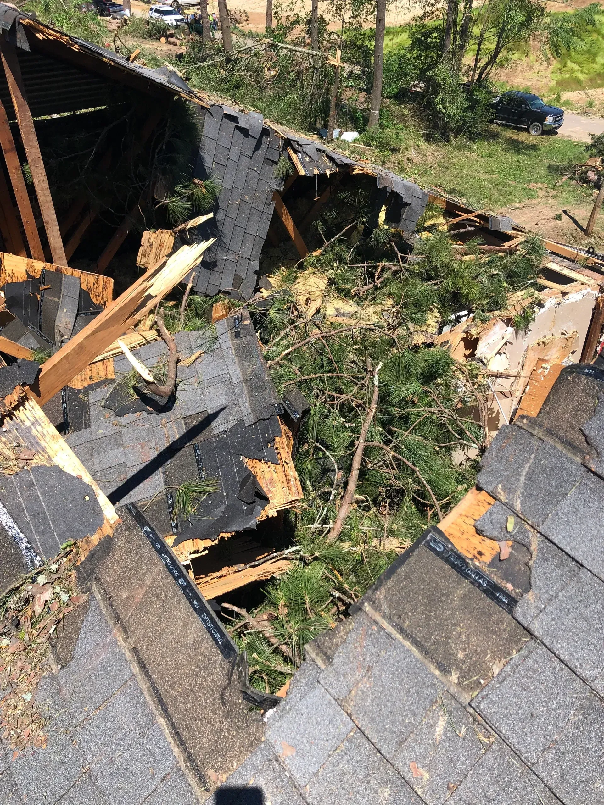Roof with large hole and collapsed shingles exposing damaged wood and debris inside.