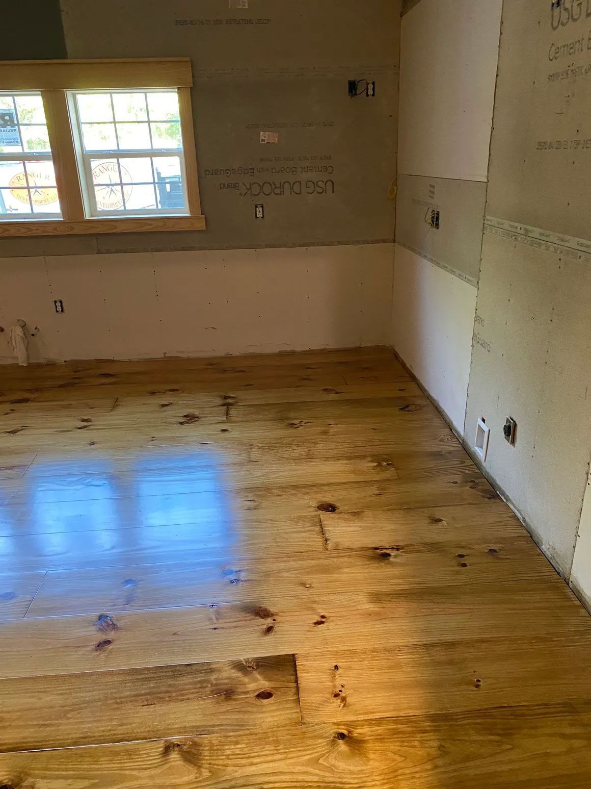 Empty unfinished room with hardwood floor and a window letting in daylight