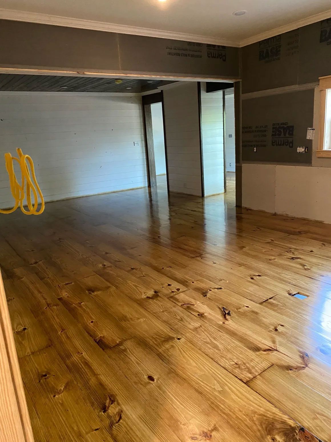 Empty room with glossy wood floor, white walls, and an open doorway near the back.