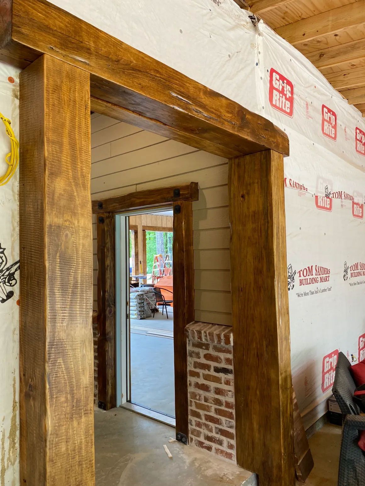 Wooden doorway framing a view into a partially finished interior with exposed insulation and brickwork.