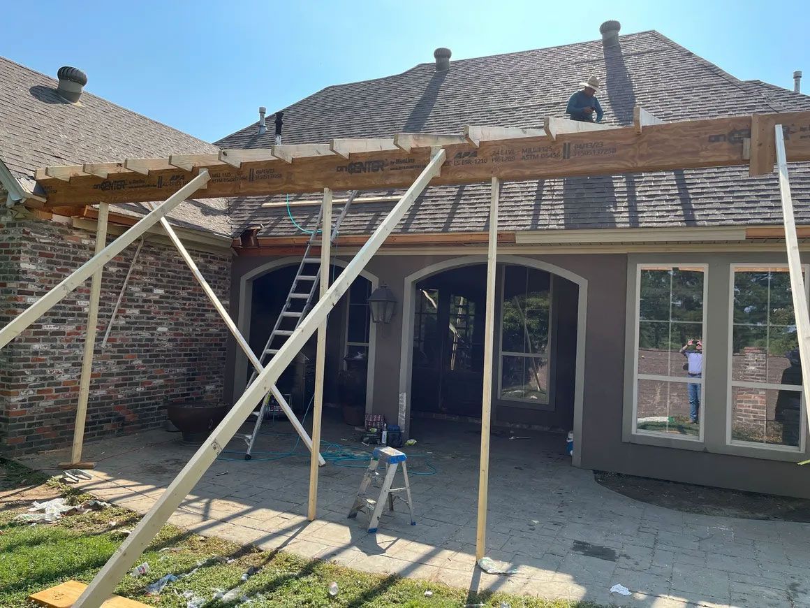 Damaged brick house with roof beams exposed and temporary support poles during repair work
