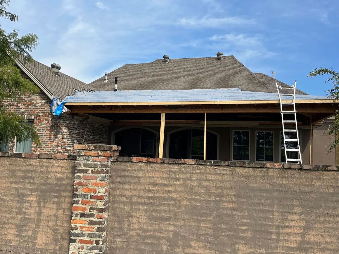 Partially renovated brick house with new roof framing and a ladder against the front