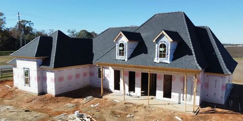 Two-story house under construction with gray roof, white walls, and front porch