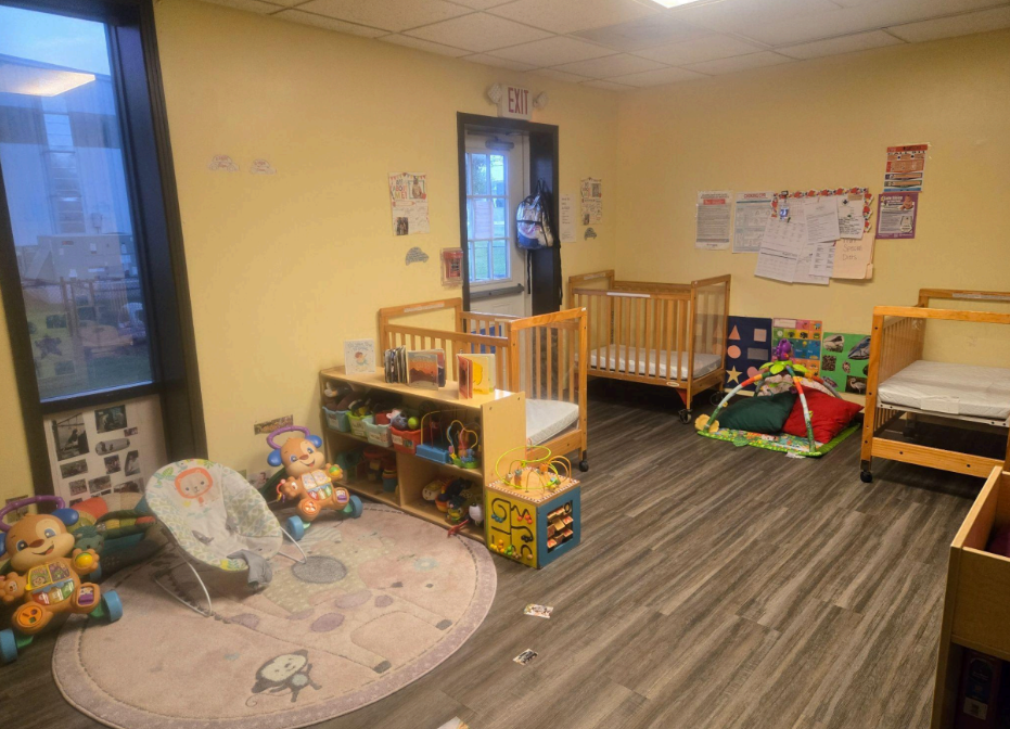 Daycare room with light yellow walls, wooden floor, and a door.