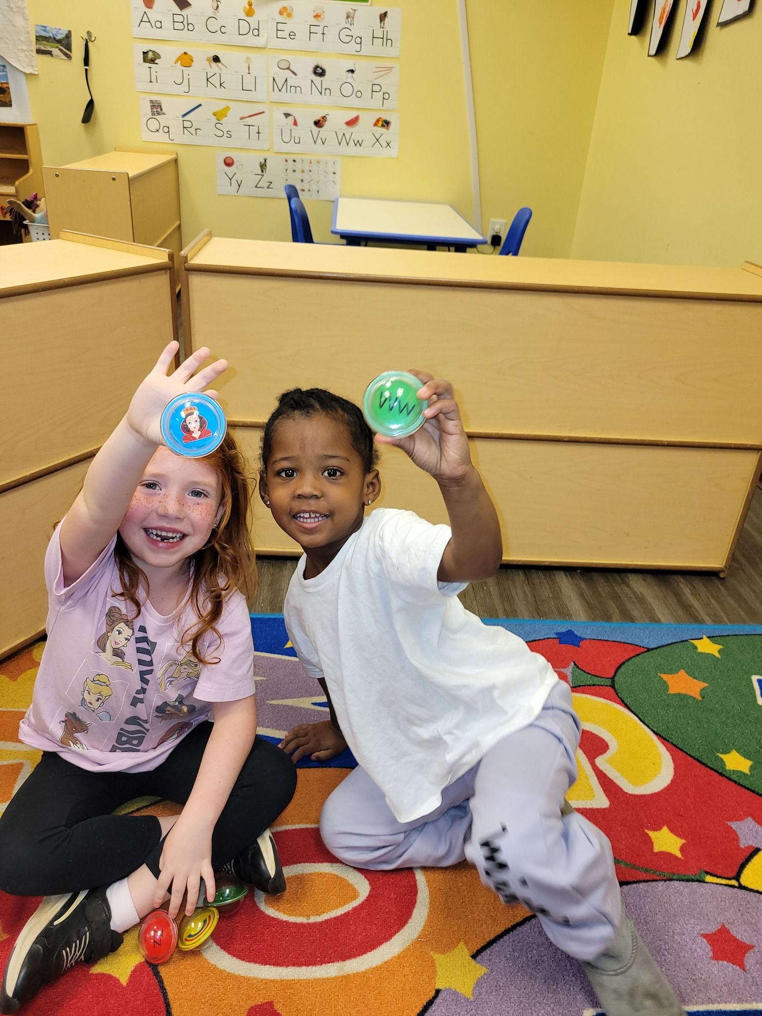 A boy and a girl are sitting on the floor holding toys in their hands.