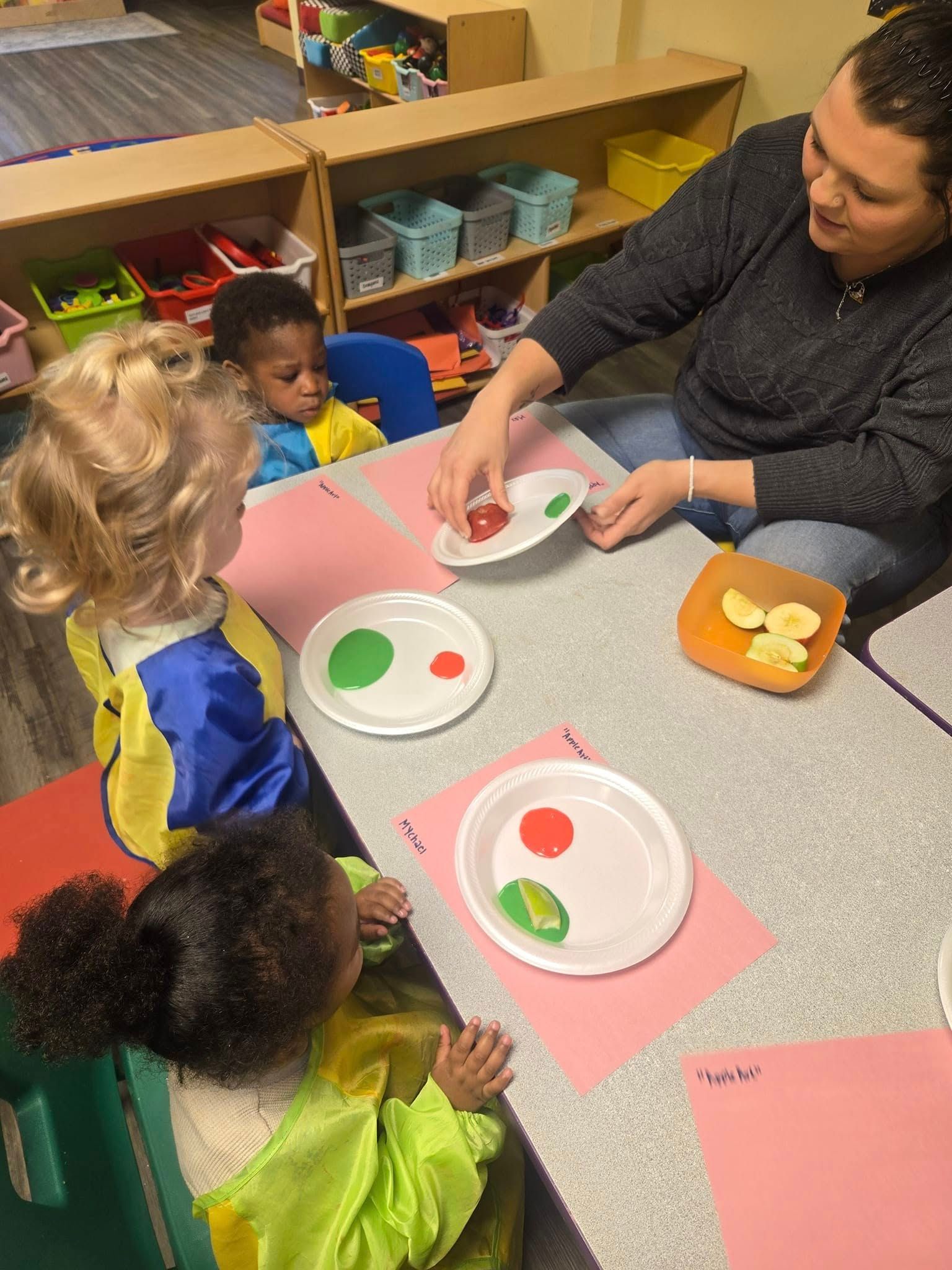 A woman is sitting at a table with a group of children.