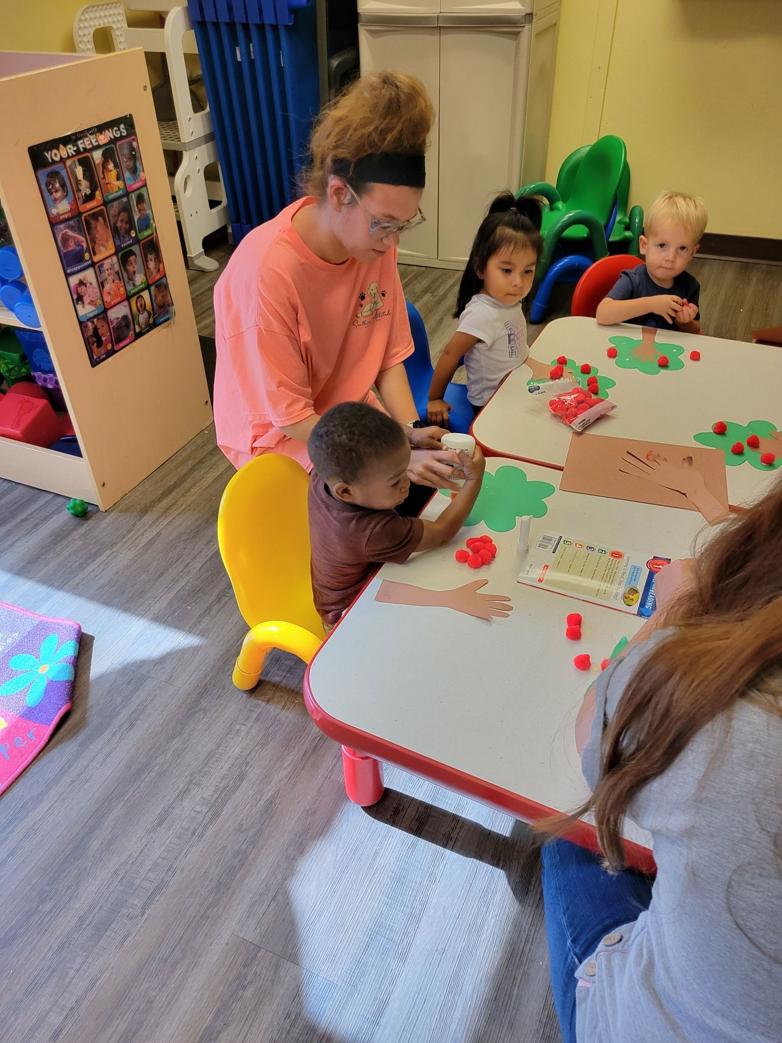 A woman is sitting at a table with a group of children.