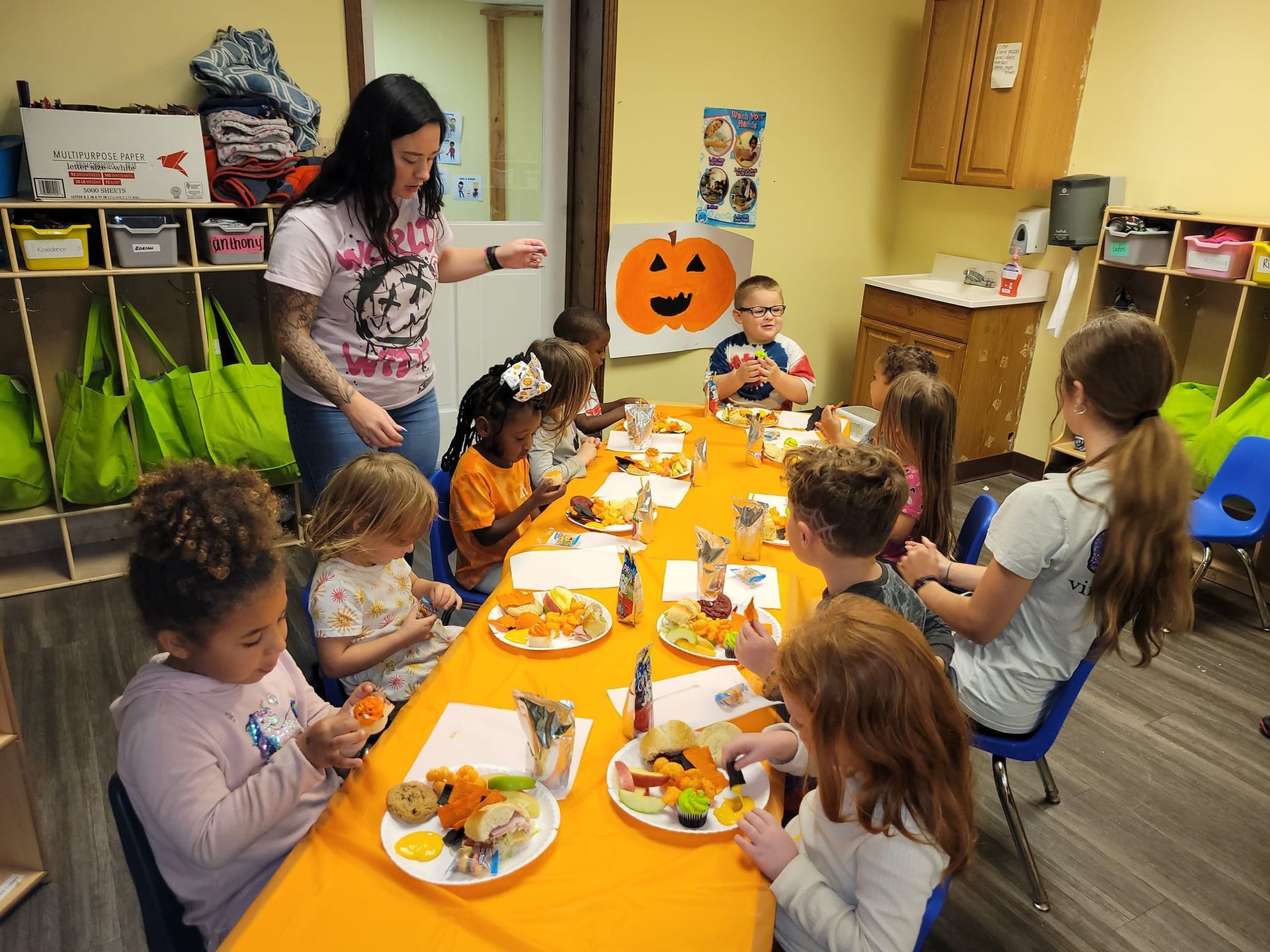A group of children are sitting at a long table eating food.