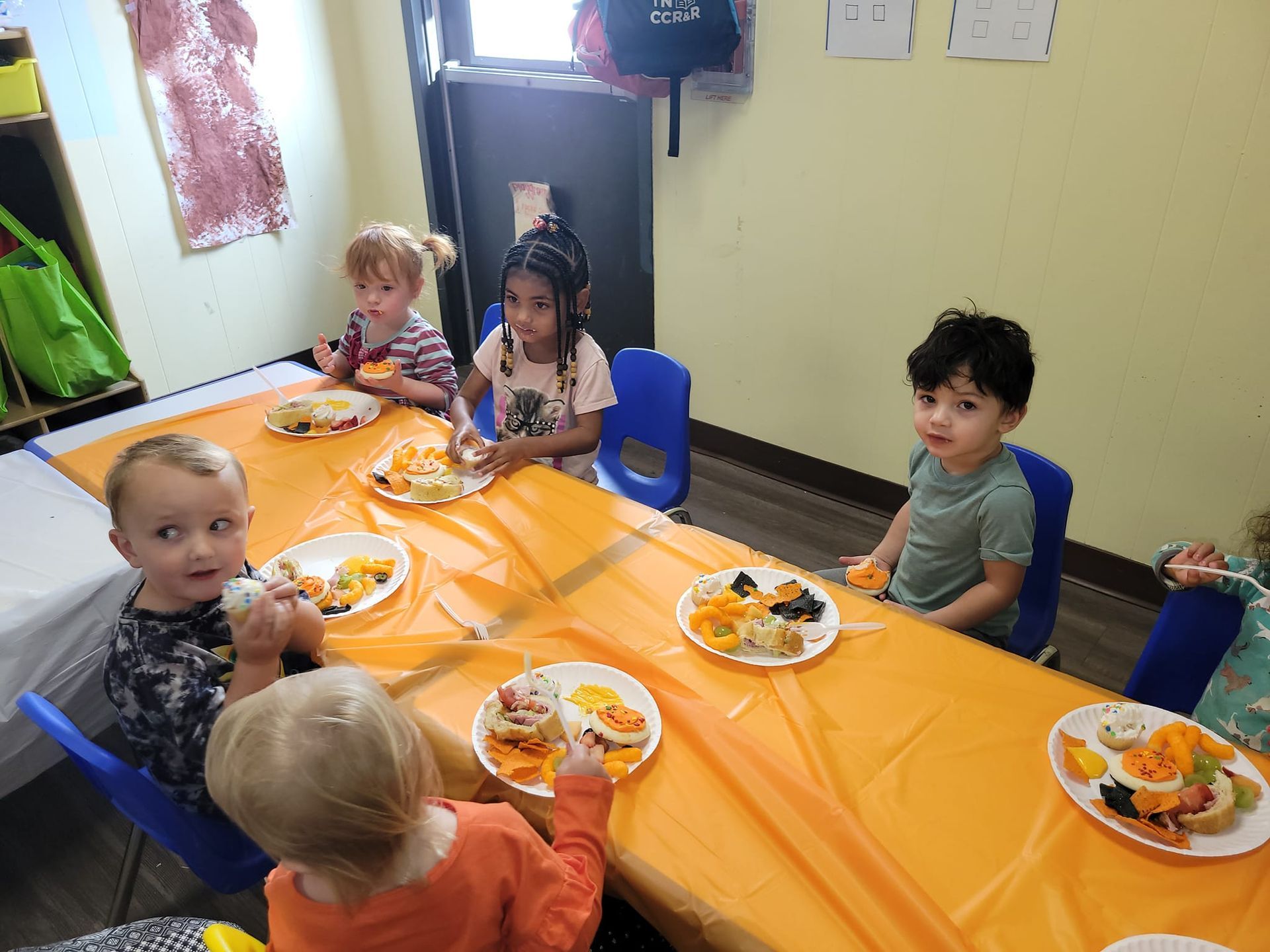 A group of children are sitting at a table eating food.