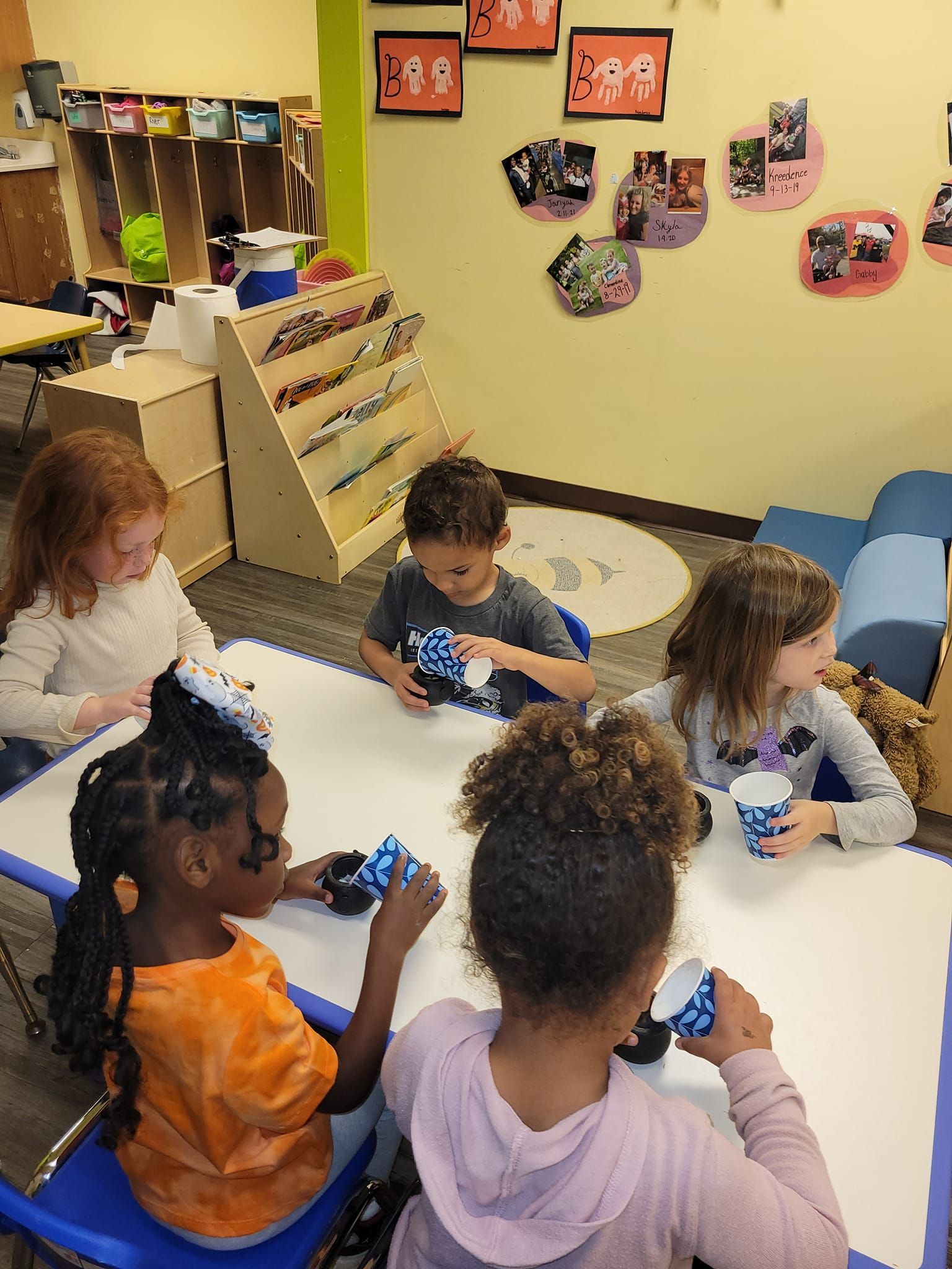 A group of children are sitting at a table eating ice cream.