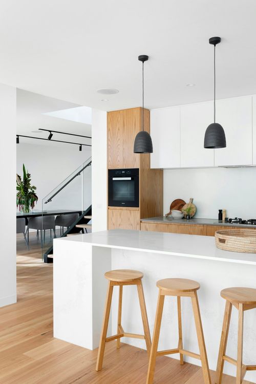 A kitchen with wooden stools and a white counter top.