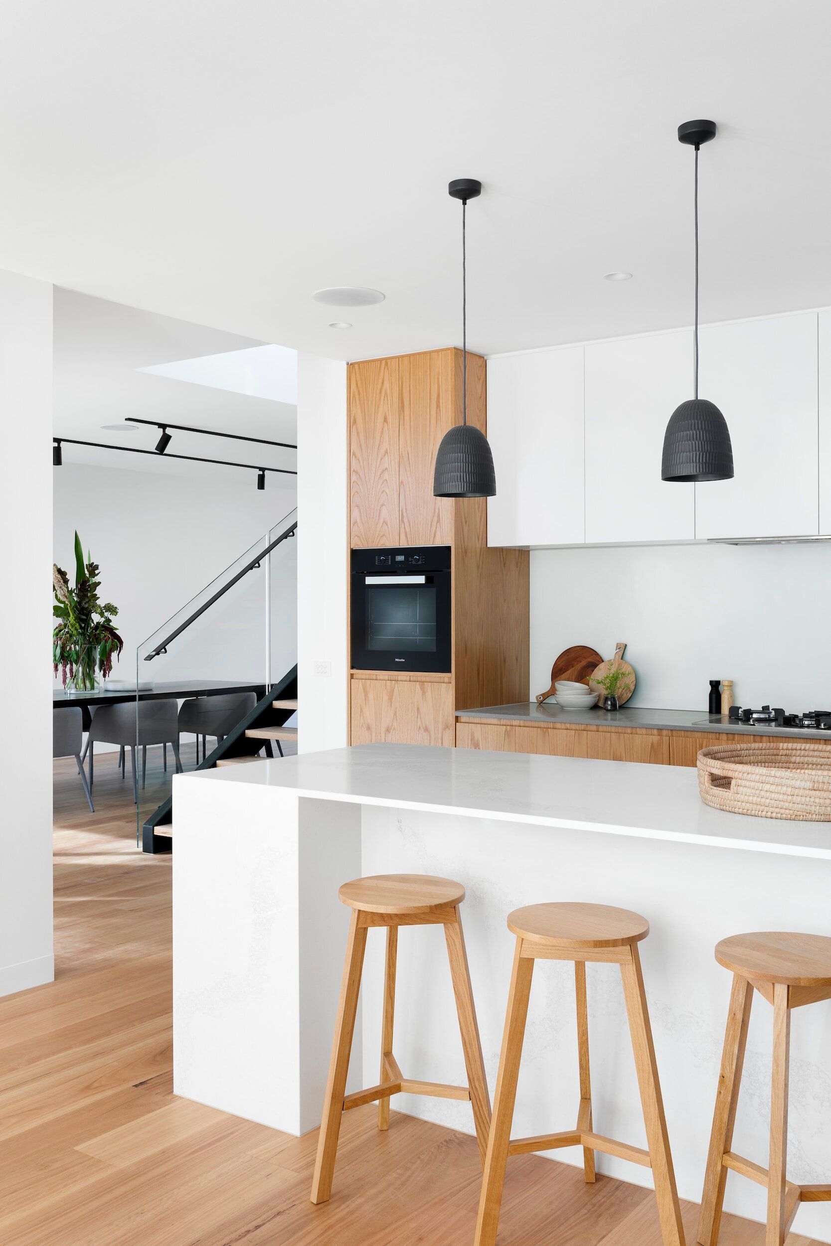 A kitchen with wooden stools and white cabinets.