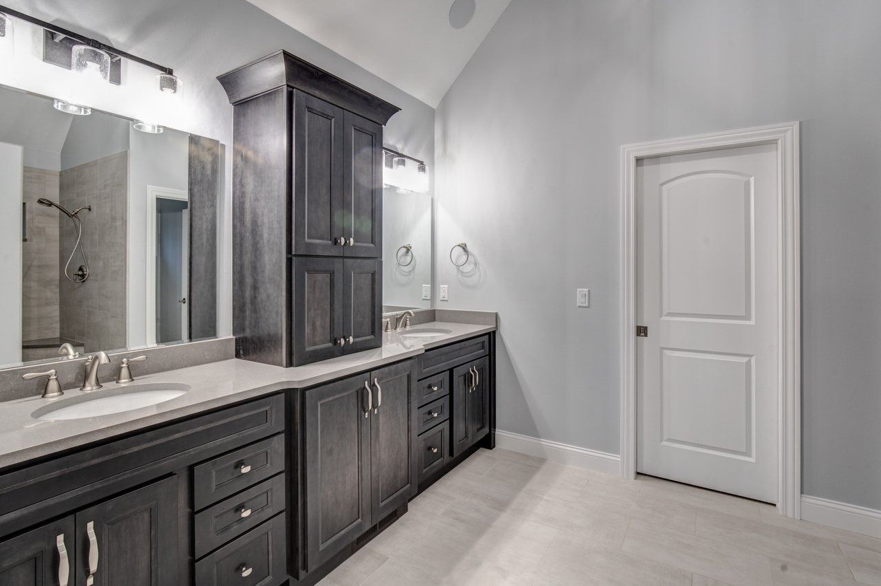 Bathroom with dark wood vanity, light countertops, large mirror, and white door.
