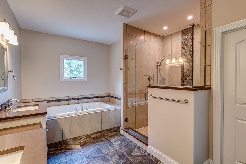 Bathroom with a tub, shower, and vanity. Beige and brown tones with tiled floors and walls.