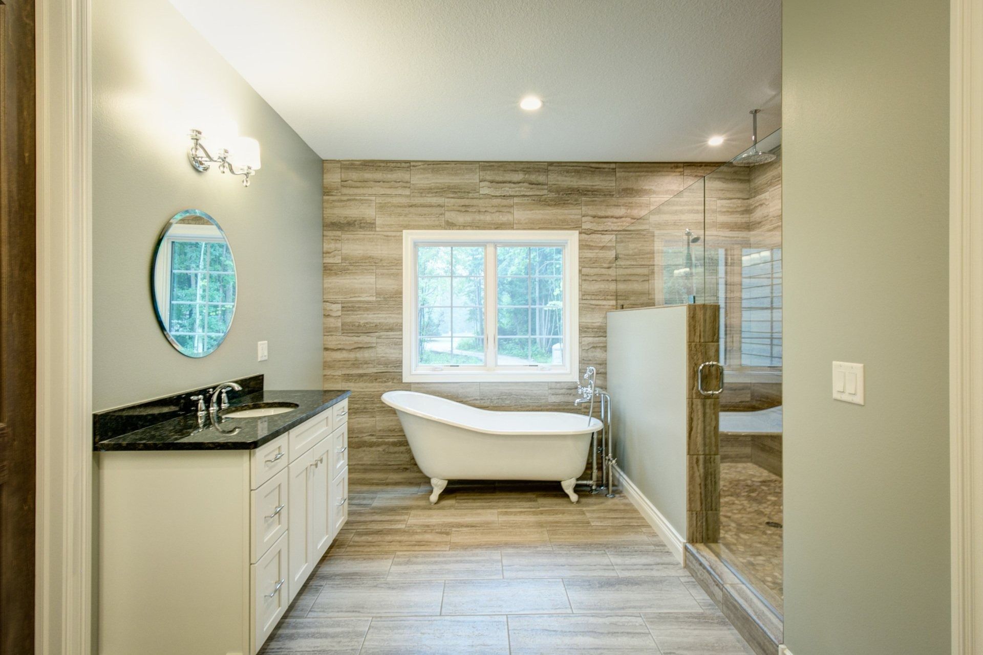 Bathroom with a claw-foot tub, glass shower, vanity, and a window with wood-look tile on the floor and walls.
