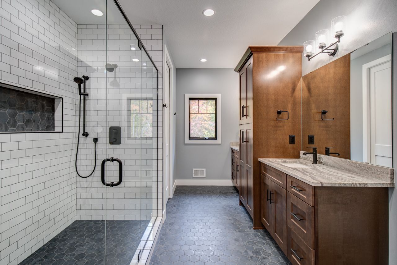 Modern bathroom with a glass shower, dark cabinets, and gray walls.