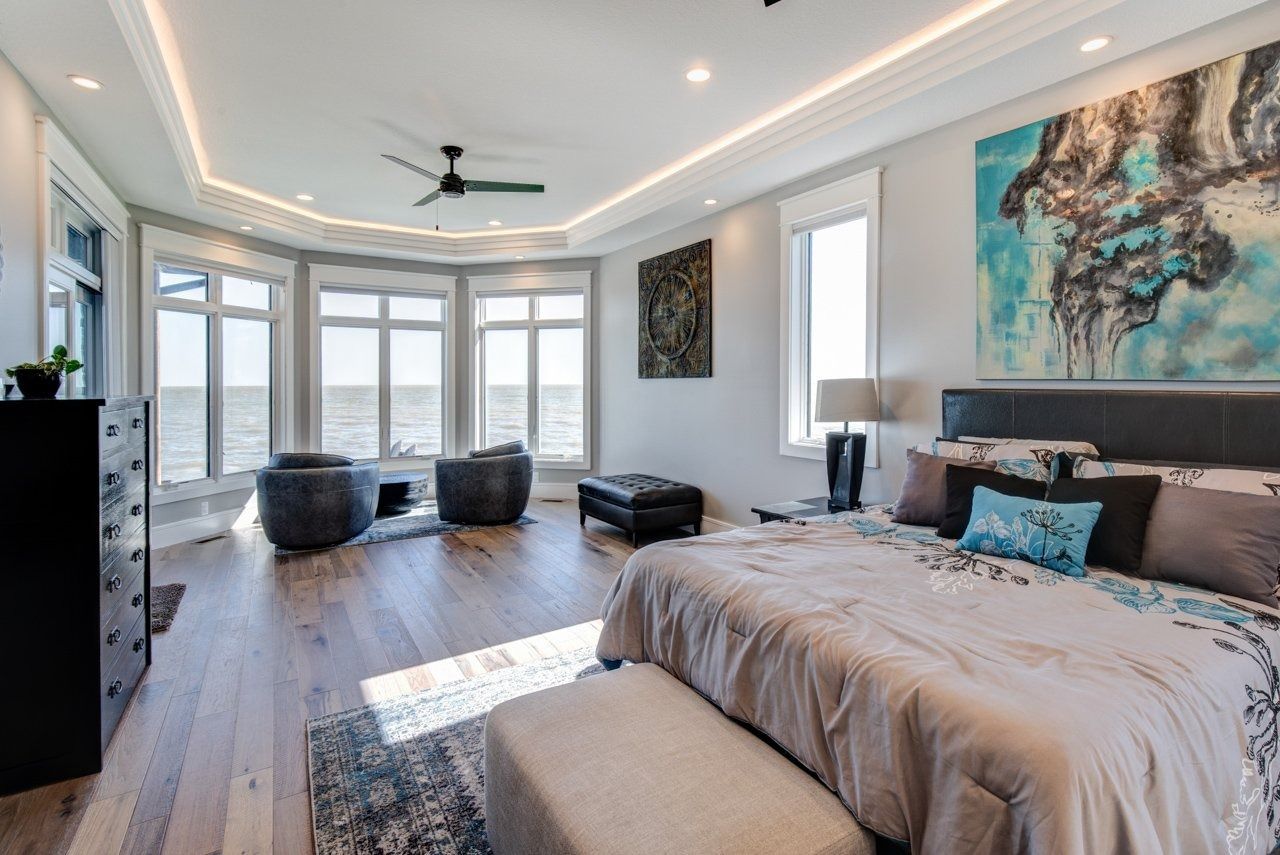 Spacious bedroom with bay windows, ocean view, large bed, and abstract artwork.