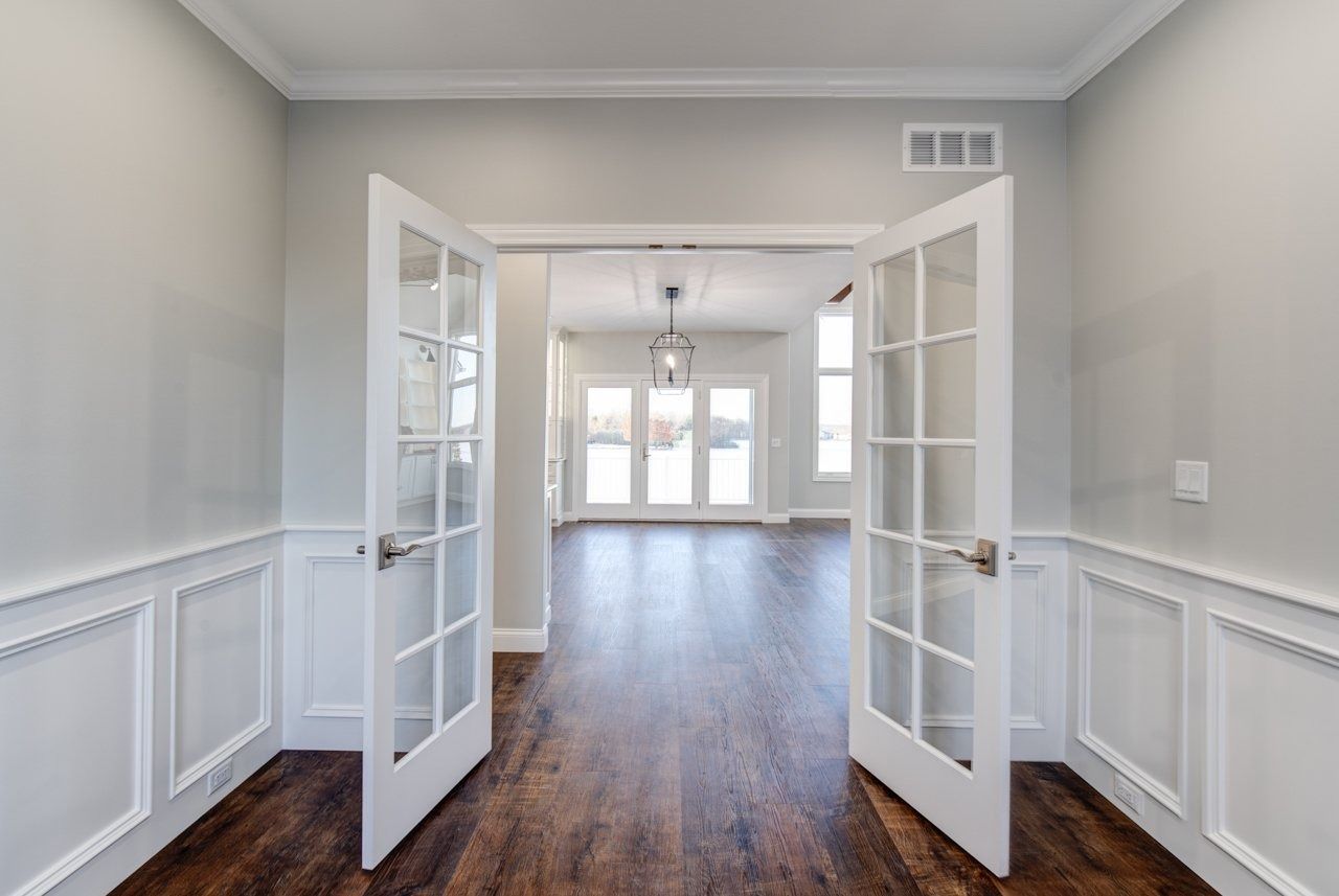 Entryway with open French doors, dark wood floor, light gray walls, white trim.