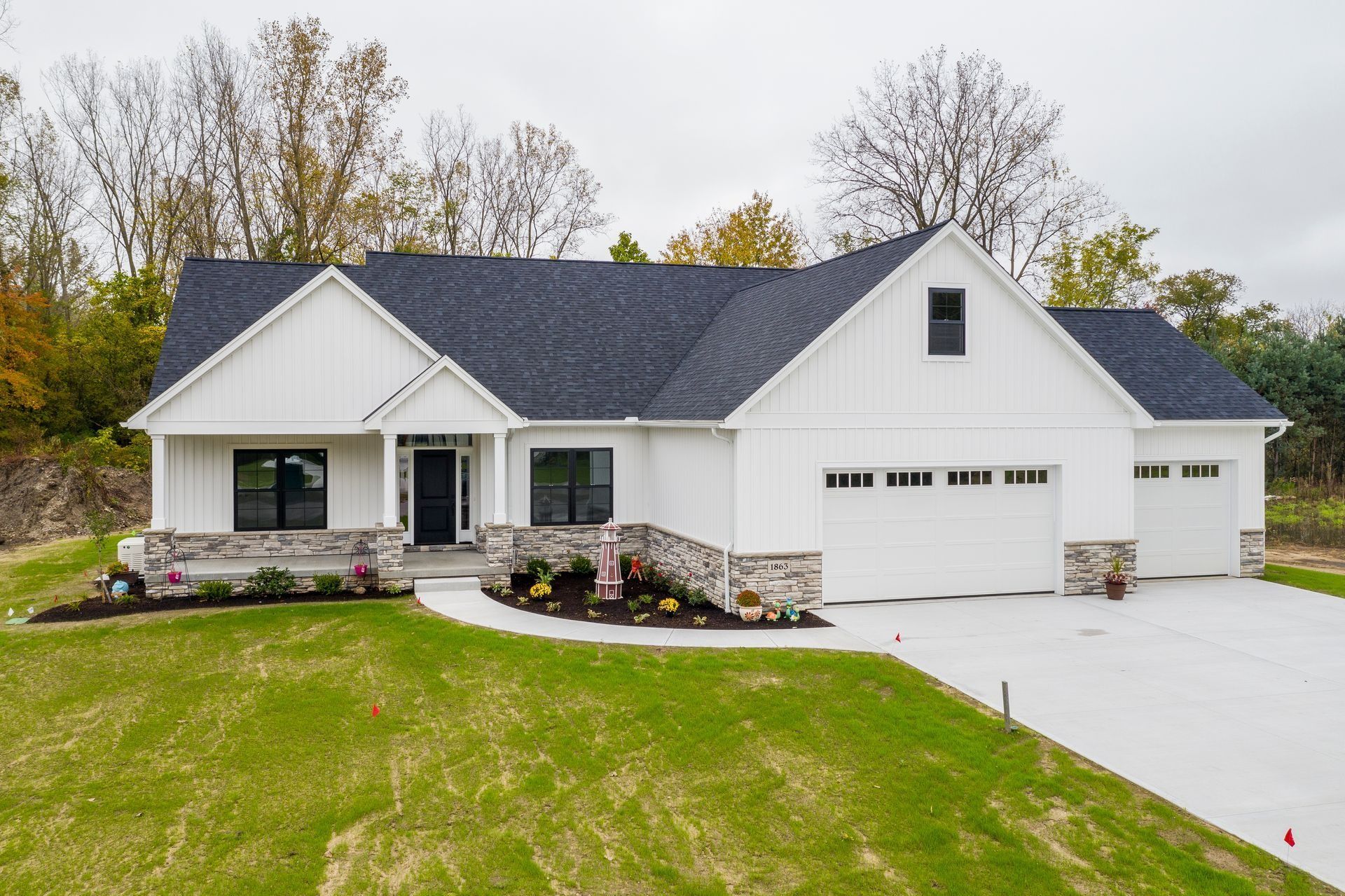 White house with dark roof and stone accents on a green lawn.