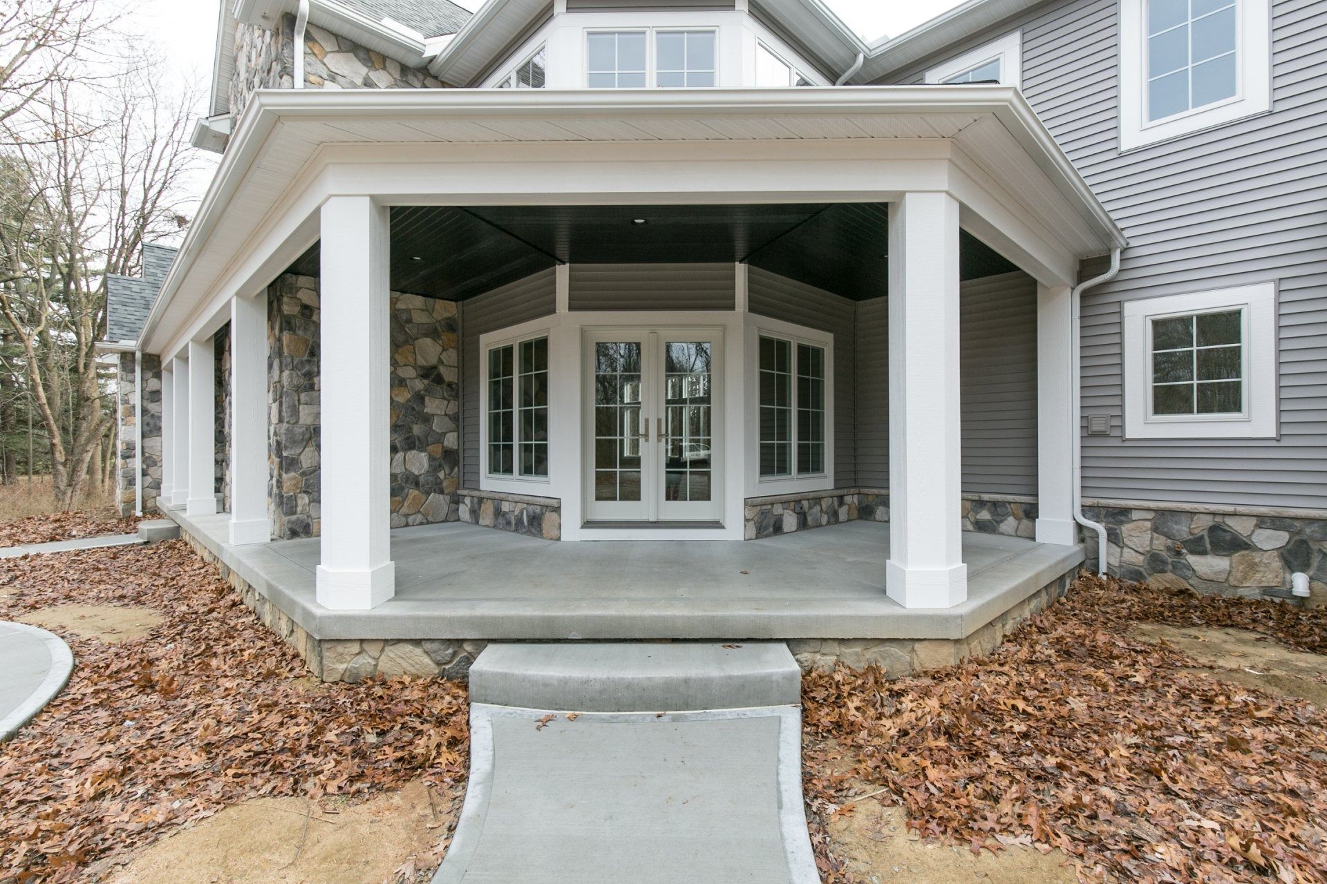 Gray house with a covered porch featuring white columns and stone accents.