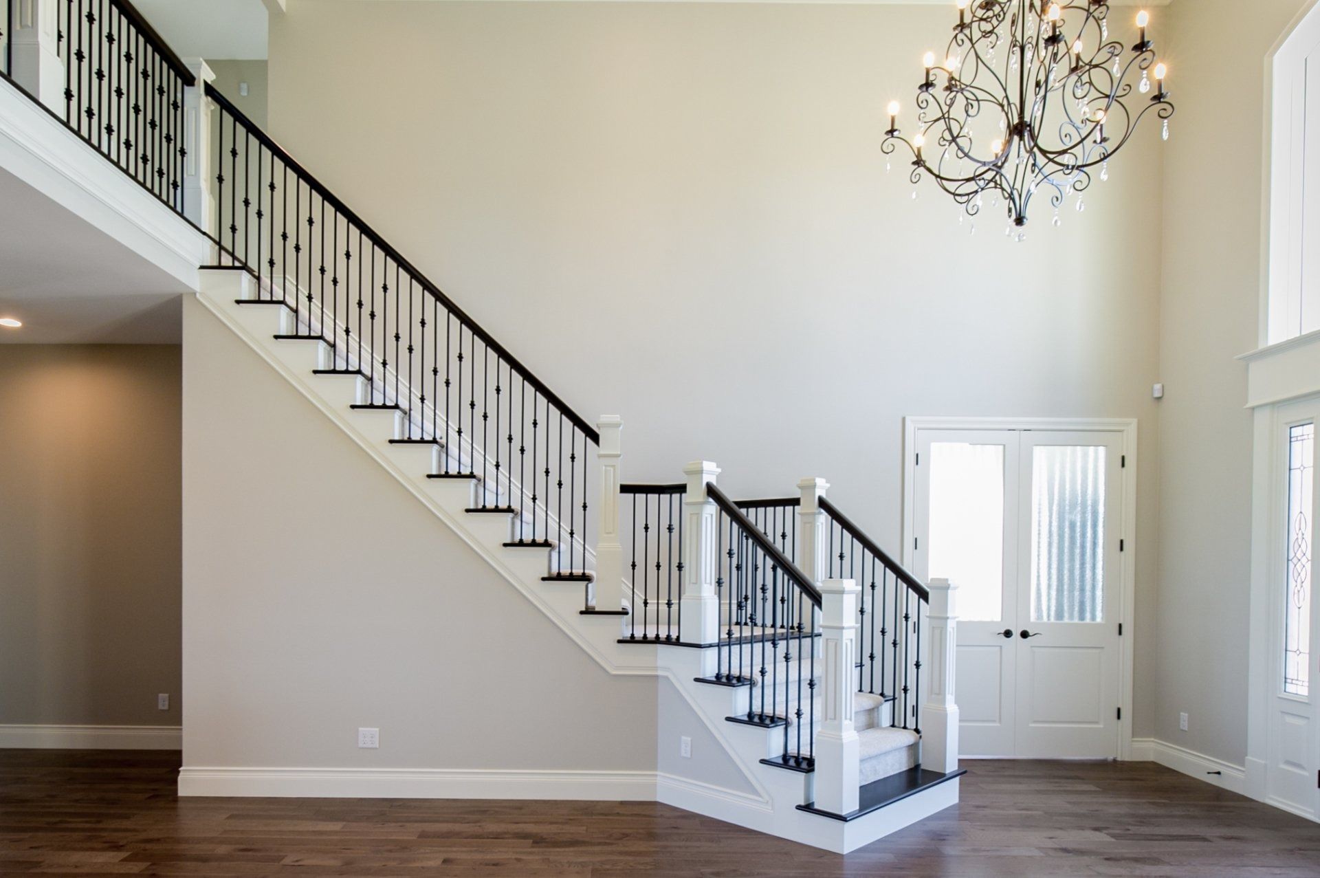 Grand foyer with a staircase, hardwood floors, and a chandelier.