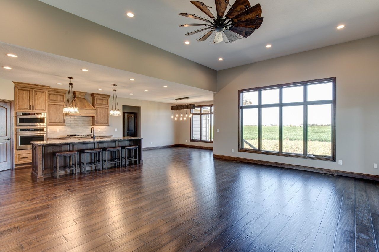 Open-concept kitchen and living area with hardwood floors, dark wood cabinets, and large windows with outdoor view.