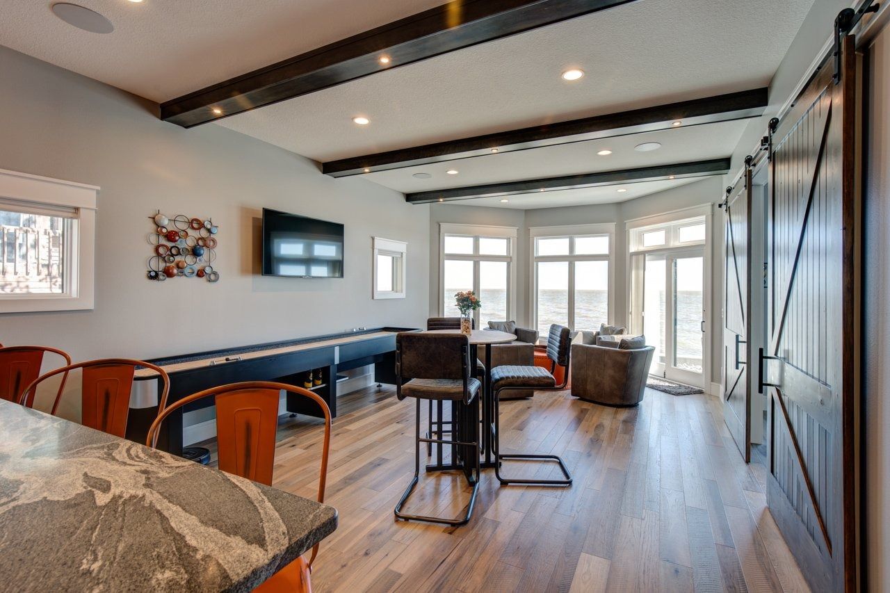 Modern living room with shuffleboard table, high-top table, and barn doors; large windows.