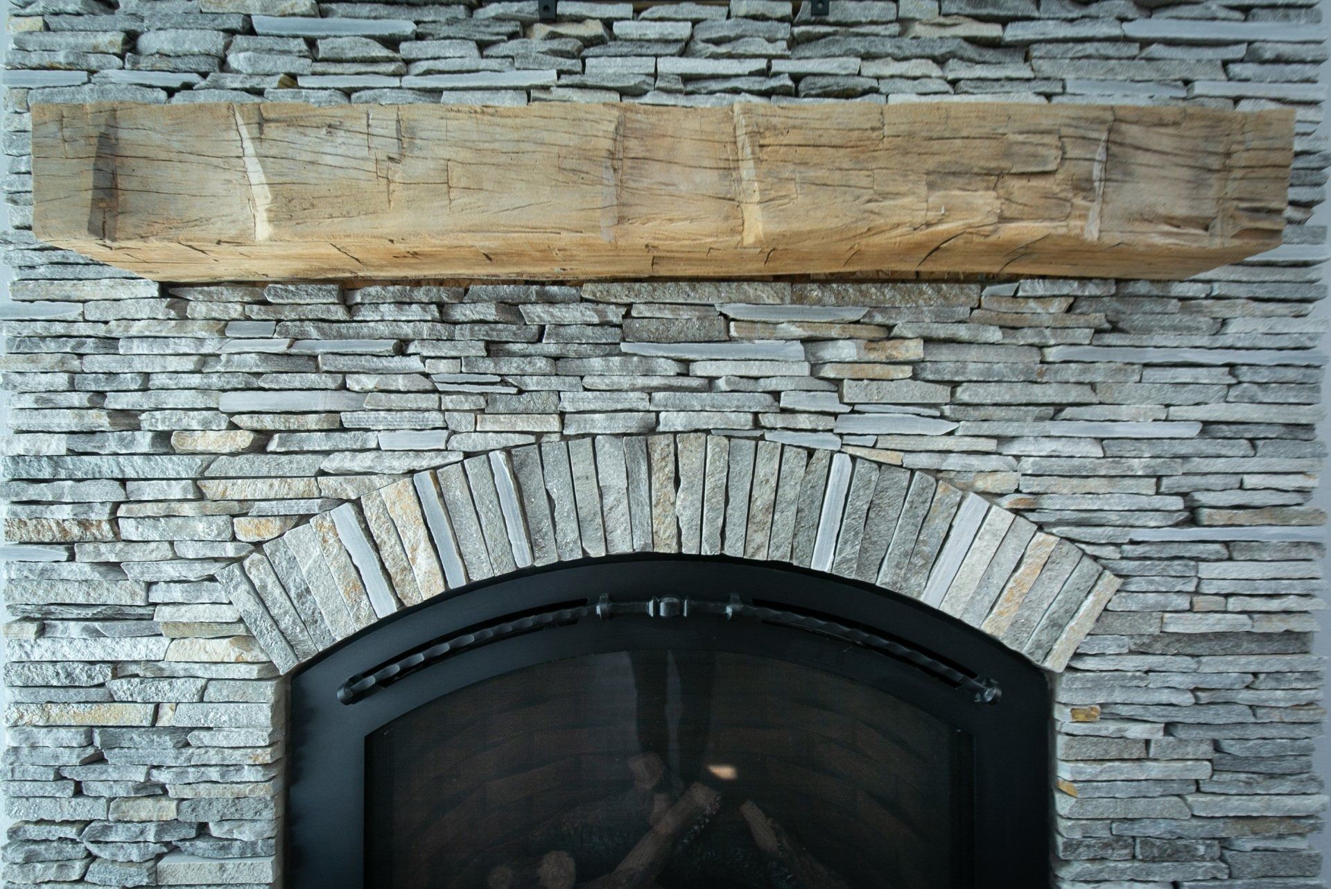 Fireplace with stone facade, arched surround, and wooden mantel.