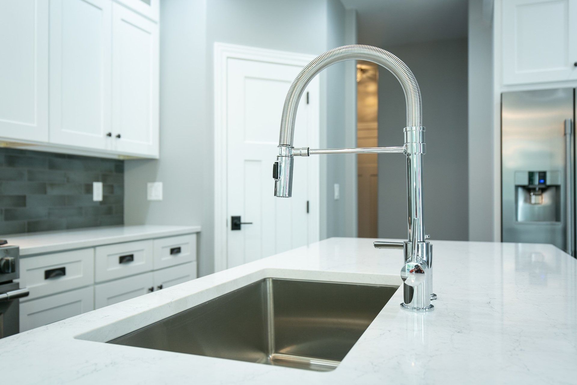 Kitchen with white cabinets, stainless steel sink, and a modern faucet.