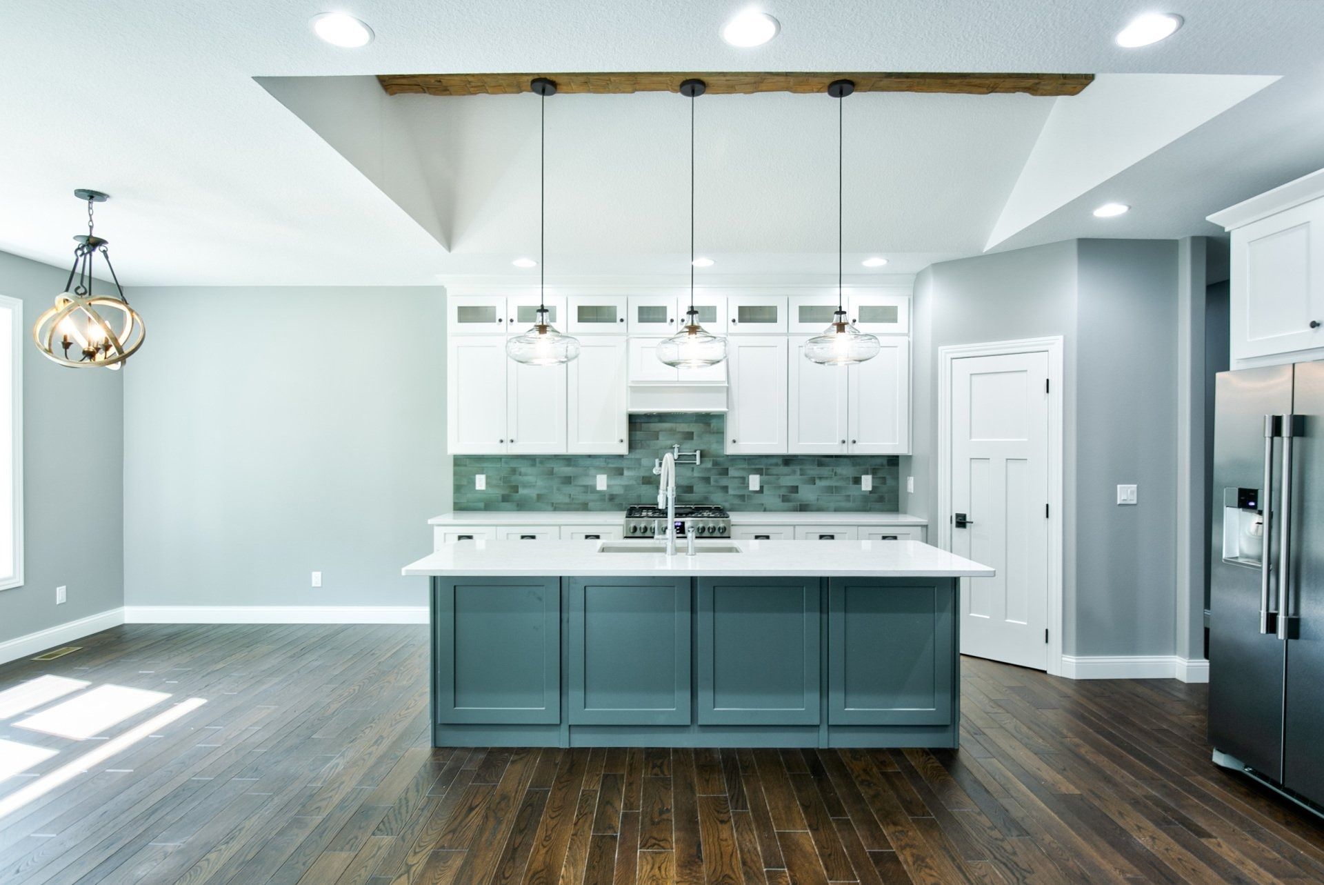 Modern kitchen with blue island, white cabinets, and dark wood floors.