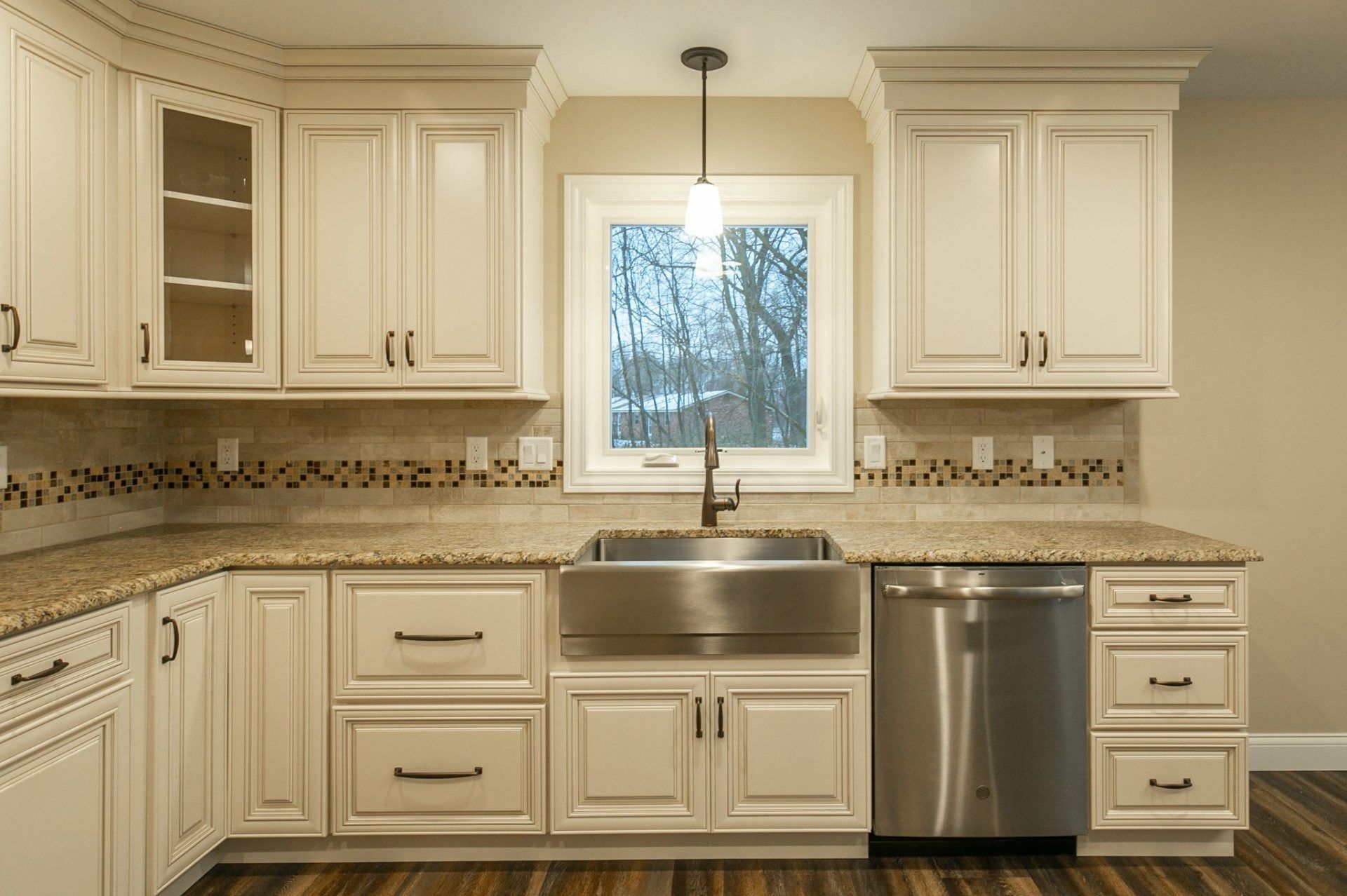 Cream-colored kitchen cabinets and stainless steel appliances with a granite countertop and a window.