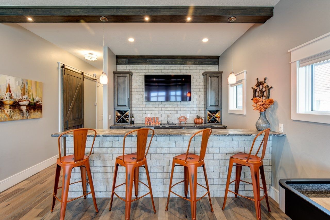 Bar with orange metal stools, a brick facade, and a mounted TV.