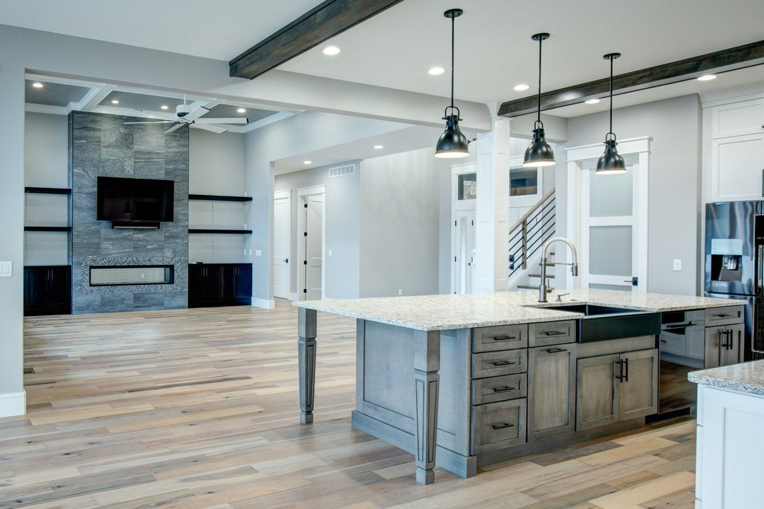Modern open-concept kitchen and living area with island, fireplace, and light wood floors.
