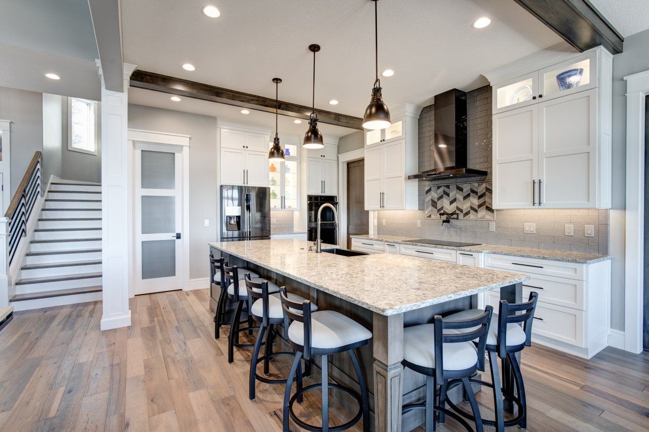 Modern kitchen with island, white cabinets, and wooden beams.