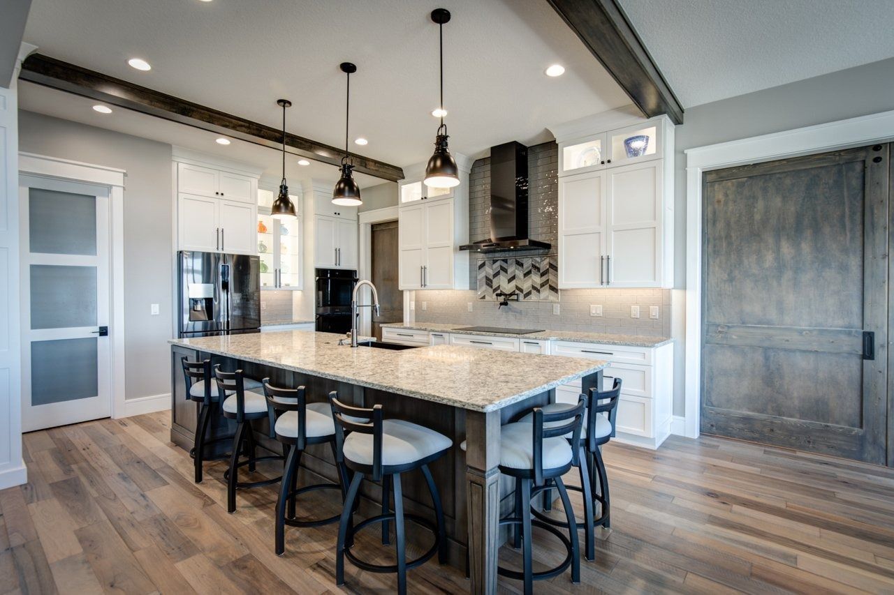 Modern kitchen with island, white cabinets, and wooden beams.