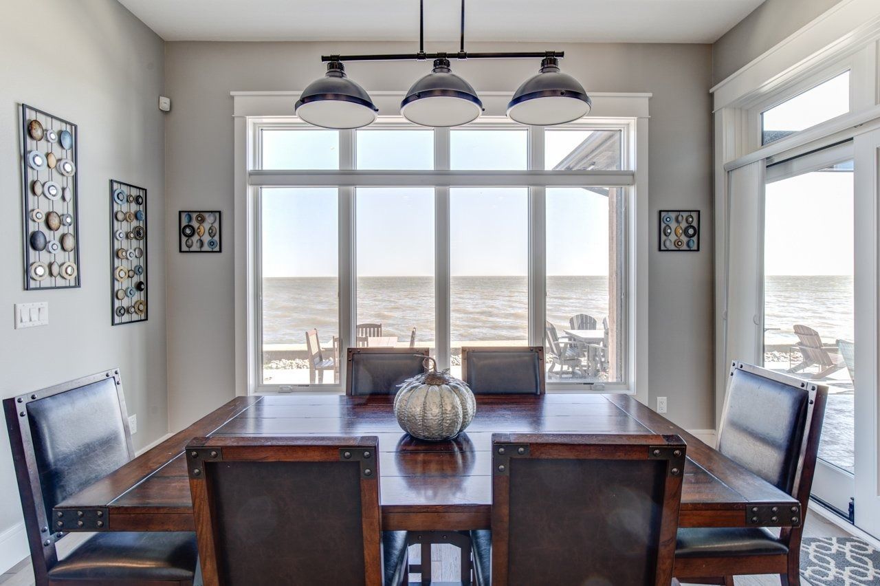 Dining room with a wooden table, chairs, and a window overlooking a body of water.