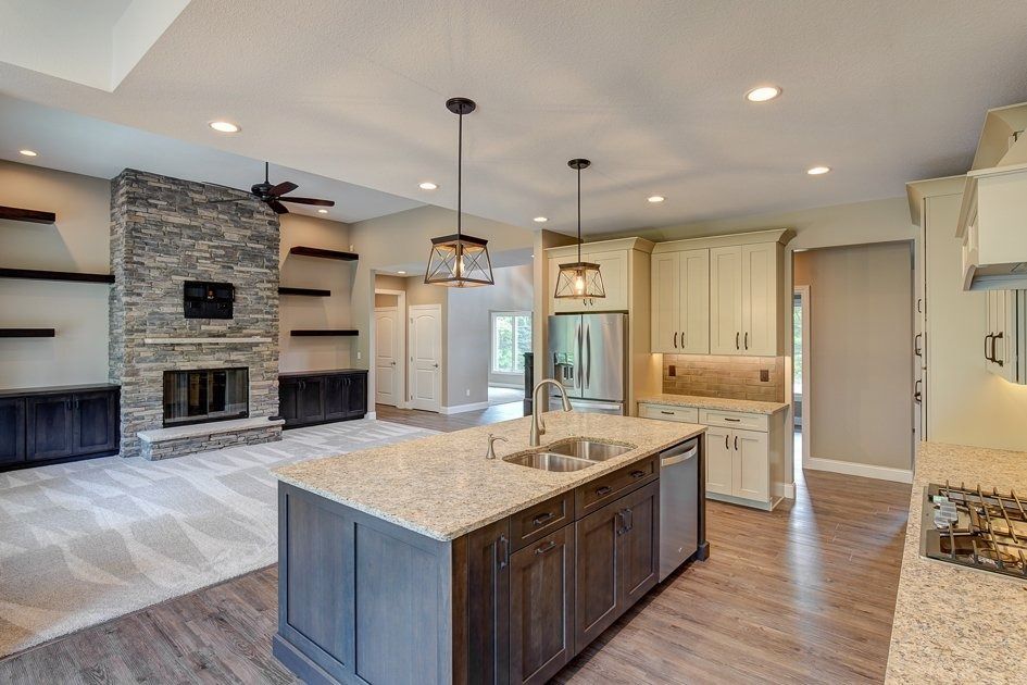 Kitchen with island, fireplace, and built-in shelving. Granite countertops, stainless steel appliances, neutral tones.