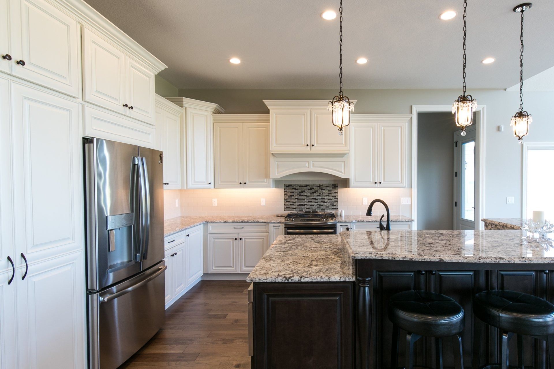 White kitchen with dark island and stainless steel appliances.